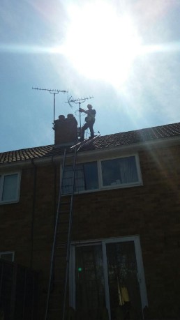 man on roof next to aerial