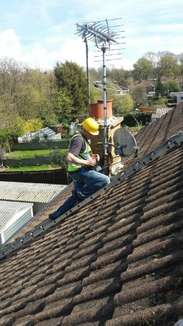 Man on roof next to satellite dish