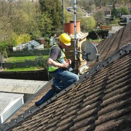 Man on roof next to satellite dish